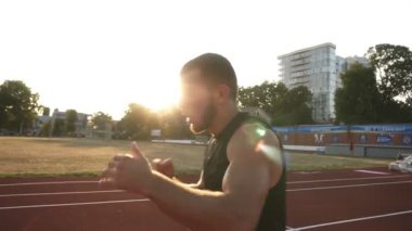 Genç bir boksör stadyum sürecinin eğitim, pratik dışarı çalışmaya başladı, kickboks. Siyah spor giyim giymiş. Güneş parlıyor ve arka plan üzerinde