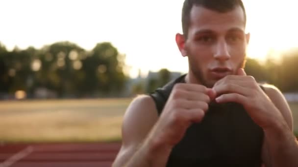 Retrato de un joven fuerte en pantalones cortos deportivos y camisetas boxeo y puñetazos oponente invisible mientras entrena al aire libre, cámara lenta — Vídeos de Stock