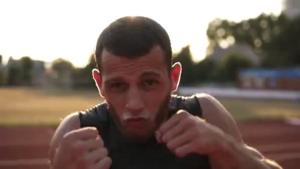 Imagens aceleradas de um jovem boxeador a exercitar-se ao ar livre. Retrato de um homem lutando boxe com oponente invisível, soco. Vista frontal — Vídeo de Stock