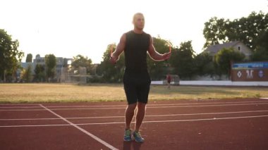 Üstünden atlayarak beyaz atlet açık havada siyah spor stadyum yolda ip atlayın. Güneş parlıyor ve arka plan üzerinde