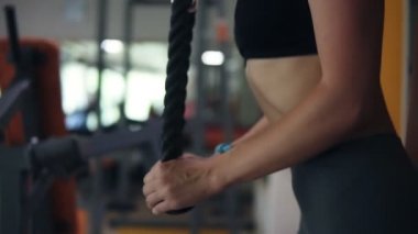 Genç bir kadın fitness sistemi ile egzersizleri yapıyor, Handhelded görüntüleri. Eğitmen geri duran ve ip ağırlıkları ile iterek sportif kız