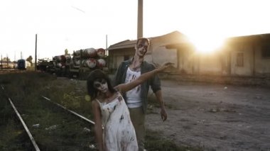 Cadılar Bayramı, filme, ürkütücü kavramı. Ürpertici zombi erkek ve kadın demiryolu hatları endüstriyel terk edilmiş yer tarafından açık havada yürüyüş kanlı giysiler içinde. Güneş parlıyor ve arka plan üzerinde