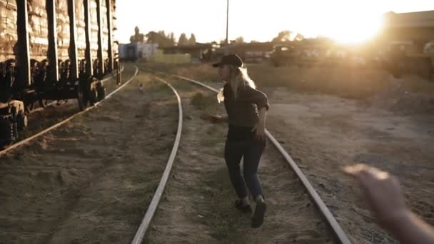 Baksidan bilder av rädd ung kvinna springer iväg från en zombie flicka av järnvägen. Solen skiner på bakgrunden — Stockvideo