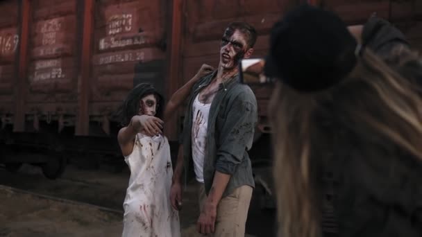 La chica del backstage haciendo una foto con su móvil de dos zombies parados frente al vagón al aire libre. Horror, halloween, concepto de puesta en escena — Vídeos de Stock