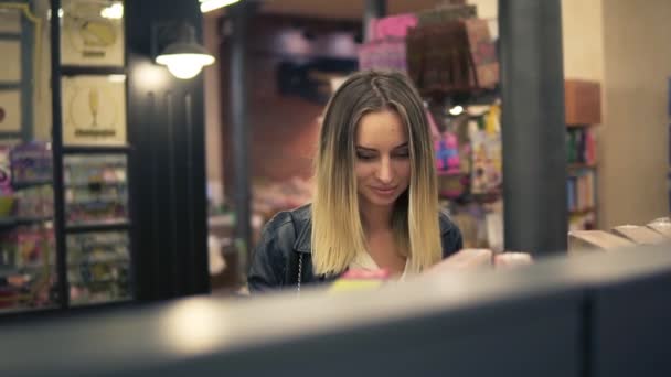 幸せな若い女が食料品店でのショッピングします。カジュアルな女をスーパー マーケットで棚から食品を選ぶします。棚の近くに立ってお客様を笑顔します。フロント ビュー — ストック動画