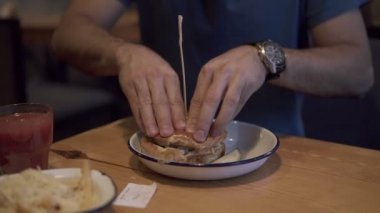 Restoranda lezzetli hamburger yemek çekici esmer genç adam. Fast food Cafe, Burger yığılmış aç genç adam burger itti ve zevk ile kapalı gözleriyle yiyor