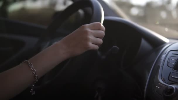 Cílem záběrů Zenske rukou řídit auto, řidič jistý. Mladá krásná dáma s náramek moderním vozem. Dívka na cestě autem — Stock video