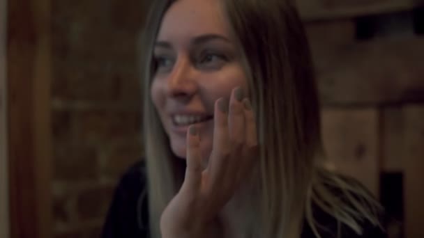 Молодая очаровательная женщина, сидящая в кафе или кафе в свободное время, привлекательная женщина с милой улыбкой, беседующая с кем-то во время отдыха в кафе — стоковое видео