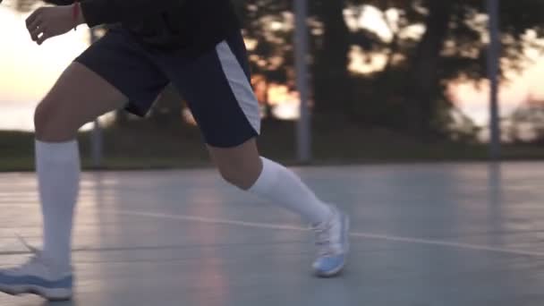 Imagens de perto de uma jovem jogadora de basquete treinando e se exercitando ao ar livre na quadra local. Vestindo roupas esportivas e meias brancas, tênis. Bom dia. — Vídeo de Stock