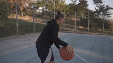 Uzun mesafe atış açık havada yerel sevilmesinde sahada pratik genç kadın basketbol oyuncusu tarafından nadir bir bakış. Ağaçlar ve güneş parlar arka plan üzerinde