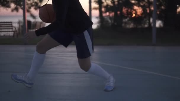 Молода баскетболістка лежить вранці на місцевому дворі. Молода дівчина біжить з м'ячем і кидає його в сітку — стокове відео