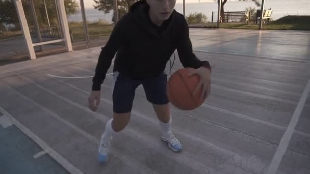 Jugadora de baloncesto en la luz de la mañana en la cancha profesional corriendo con pelota. Imágenes de mano. De cerca. — Vídeos de Stock