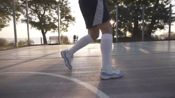 用白色高尔夫球袜和运动鞋关闭女性运动员腿的镜头。女 baasketball 球员弹跳球从手到手。阳光照耀背景 — 图库视频影像