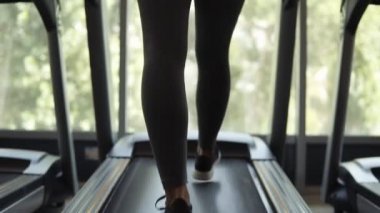 Muhteşem manzara kadar aşağıda Siyah sutyen ve bir koşu bandı üzerinde ısınma tozluk uygun bir kadının spor salonu panoramik pencerede ön alt. Arka görünüm