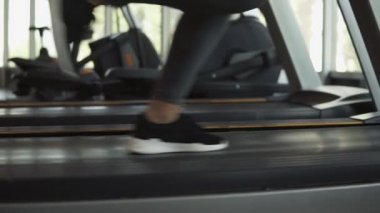Bayanlar fitness Club bir koşu bandı üzerinde çalışan snakers ayaklarda portre görüntüleri. Gri tozluk ve spor salonunda egzersiz spor sutyen sarışın kadın