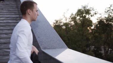 Beyaz genç adam bisiklet merdivenlerden yakınındaki durdu onun laptop çubuğunda koyar. Wareless açık havada çalışan beyaz gömlek gülümseyen adam