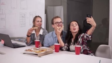 Çeşitli mutlu iş arkadaşlarınızla pizza ofis ve alma selfie tatilinde mutlu bir şekilde hep birlikte yemek. Modern, aydınlık office