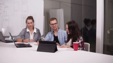 Gözlük ve yaratıcı çalışma alanı'ndaki office masada oturan iki kadın genç adam. Onun vizyonu paylaşan esmer kadın whitesheet tahtada işaret. Adam ayağa kalktı ve sahip devam