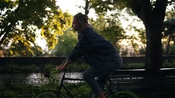 Bastante hembra montando en bicicleta en el parque matutino o boulevard. Vista lateral de una mujer joven montando una bicicleta de trekking. Vista de cerca — Vídeos de Stock