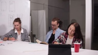 Üç girişimciler veya birlikte çalışma belgeleri, karşılaştırma bir ofis büro içinde oturan öğrenciler notlar. Genç adam bir kitap okuma orta