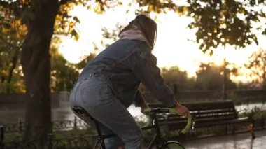 Güzel erkek sabah park veya boulevard bir bisiklet sürme. Genç bir kadın mavi jeans şehrin boş iken bir trekking bisiklet sürme