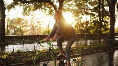 Çok beyaz kadın sabah park veya boulevard bir bisiklet sürme. Spor ayakkabı, rahat kıyafetler giymiş bir trekking bisiklet sürme genç bir kadın yan görünüm