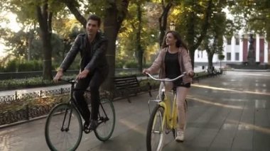 Genç çift ya da arkadaşlarınızla yaz aylarında boş şehir parkı veya Bulvarı bisiklet sürme. İnsanlar, eğlence ve yaşam tarzı kavramı. Mercek parlaması