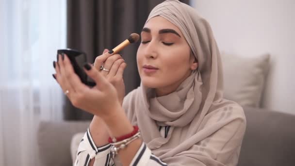 Mulher muçulmana fazendo maquiagem em seu rosto com escova. Vida moderna de pessoas muçulmanas. Maquiagem em casa. Quarto interior Loft — Vídeo de Stock