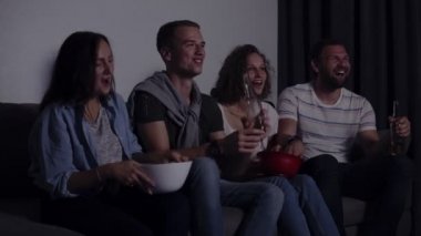 Kanepede, dört sit dostları Tv. Kafkas genç grup oturup kanepe, içecekler ve aperatifler komik film izle. Film gecesi