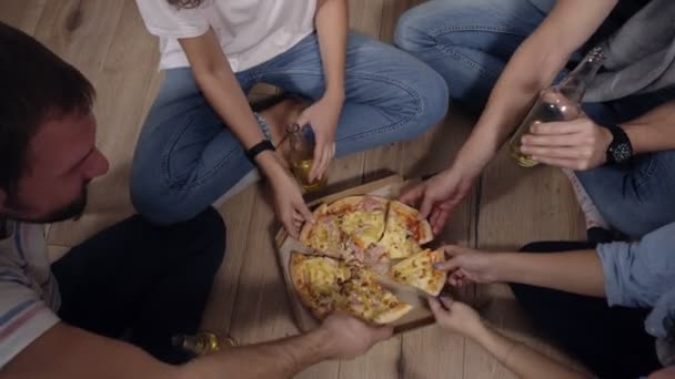 Friendship, food, domestic party time - cheerful caucasian friends order pizza, having fun, sitting on floor indoors and laughing, eating, drinking. Top view — Stock Video