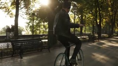 Bisiklet Park trekking siyah bisiklet sürme kulaklık olan genç adam. At binme ve en sevdiğiniz müzik dinlerken dans. Güneş parlıyor ve arka plan üzerinde