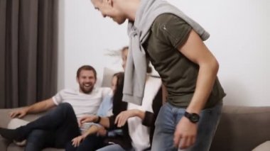 Dostluk, iletişim, parti zamanı - neşeli beyaz arkadaş birlikte eğleniyor, kapalı gri bir kanepede oturan ve gülerek kucaklayan