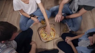 En iyi pizza ile kutusunun altındaki sonra el el alarak gençlerin bakmak sıcak lezzetli pizza dilimlerini karton kutu. Ahşap zemin, içecekler ve pizza yerdeki siting