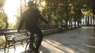 Bisiklet Park trekking siyah bisiklet sürme kulaklık olan genç adam. Nohands ile en sevdiğiniz müzik dinlerken sürme. Arka planda güneş parlar. Görünümünde nadir