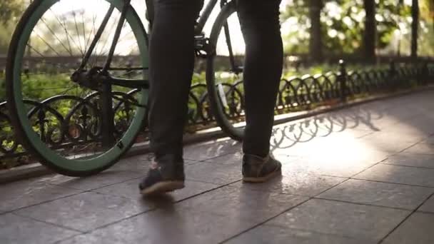 Manliga ansiktslösa ben gå med cykel på asfalterad väg närbild sida Visa aktiv livsstil. Mannen i svart troussers börjar rider sin trekking cykel på gatan eller grön park. Hälsosamt liv sommaren utomhus — Stockvideo