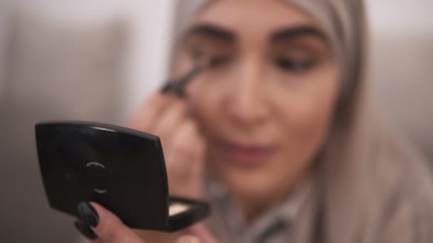 Muslim woman doing contour on her eye using black eyepencil. Modern life of muslim people. Front view of a woman in beige hijab — Stock Video