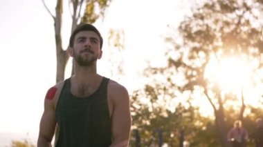 Önden Görünümü tarafından yerel spor bahçesinde birkaç kırmızı bantları ellerinde yürüyüş sonra yatay bir çubuk üzerinde atlama sakallı adam. Ağır çekim