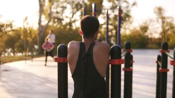 健身, 肌肉发达的男子在衬衫来到当地的运动场, 并开始在水平横梁上训练。罕见的风景。夏季时间 — 图库视频影像