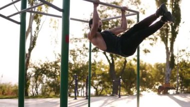 Fitness, spor, eğitim ve insan kavramı - güçlü parkta yatay çubuk üzerinde asılı iken bacak egzersizleri yapıyor adam sakallı. Abdominal ve bacaklar açık havada spor salonunda egzersiz