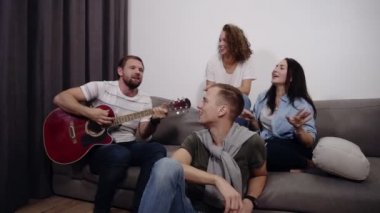 Mutlu arkadaş kanepede oturup ve akustik gitar çalmak adama dinle. Birlikte arkadaşlarım ile iyi vakit geçirmek için olsun. Müzik ve şarkı oturma sırasında dans ritim, hissediyorum