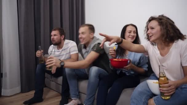 Perusahaan Kaukasia dari teman-teman muda menonton pertandingan di TV dengan minat, pengalaman dan mengungkapkan emosi mereka terang, mencatat kemenangan tim favorit mereka. Mereka berteriak, mengangkat tangan mereka, berdiri — Stok Video