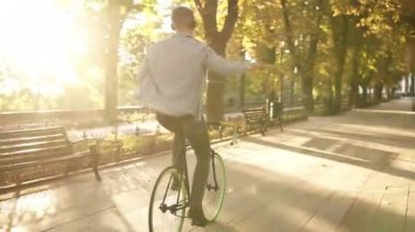 Müzik siyah Kulaklığımda mutlu genç adam binicilik bisiklet park ve dinler. Adam uzanmış eller. Keyfi, parkta açık havada asılı. Görünümünde nadir