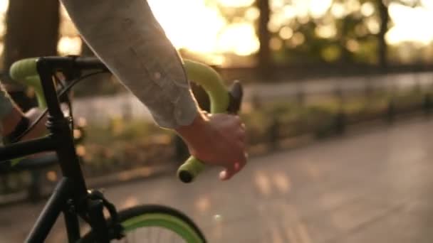 Närbild bilder av roder - manliga cykling cykel i morgon parken eller boulevard. Sidovy av en ung man rider en trekking cykel. Solen skiner på i bakgrunden, dimsyn — Stockvideo