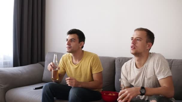 两名兴奋的成年男子在电视机上喝啤酒, 在室内看足球比赛。庆祝胜利, 喊话, 给高五。特写 — 图库视频影像