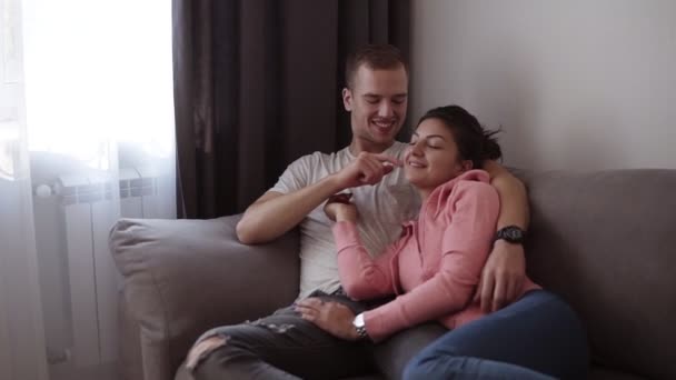 Pareja relajándose juntos en el sofá. Romántica joven feliz pareja tumbada en casa en el sofá descansando divirtiéndose juntos, jugando. Loft habitación interior — Vídeo de stock