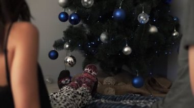 Güzel ile katta yer sıcak kış süs çorap giyen erkek ve kadın ayak Noel ağacı ve Noel oyuncaklar arka planda dekore edilmiş. Birlikte eğleniyor. Arkadaki görüntüleri
