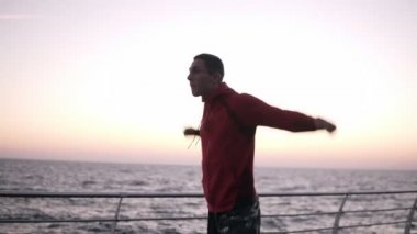 Bir sabah egzersiz sırasında bir atlet ısıtır boks maçında nişanlı. Beyaz adam egzersiz, denize yakın ahşap Promenade ellerini uzatır