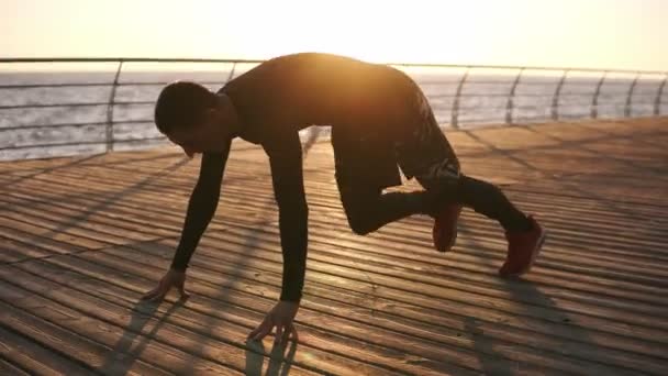 Foto van een jonge sporter doen push ups buitenshuis op de houten froor in de voorkant, de zee of de Oceaan. Fitness en oefenen aan de kust. Sport, recreatie, boksen levensstijl concept — Stockvideo