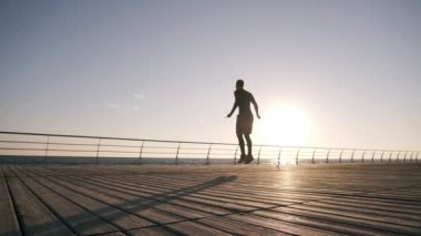 Uzun boylu ince genç adam ile deniz kenarında ip atlama egzersiz silüeti. Genç adam açık havada çalışma boks yapan. Ağır çekim. Düşük açılı görüntüleri. Steadicam