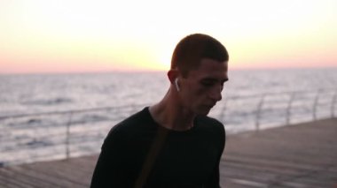 Üstünden atlayarak beyaz atlet açık havada siyah spor giyim ipin atlayın. Arka planda güneş parlar. Seaside